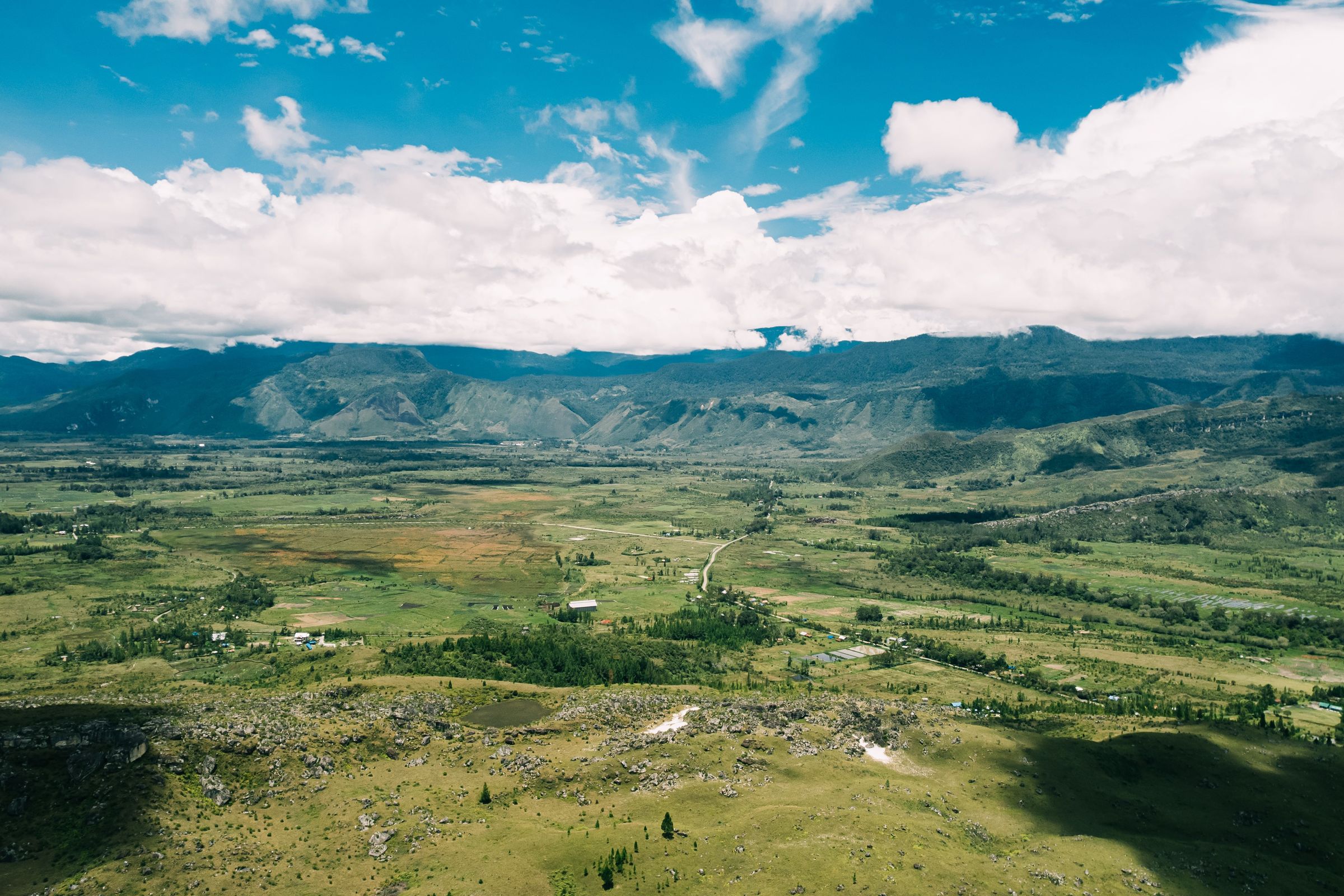 A wide green highland valley ringed by forested mountains in Papua